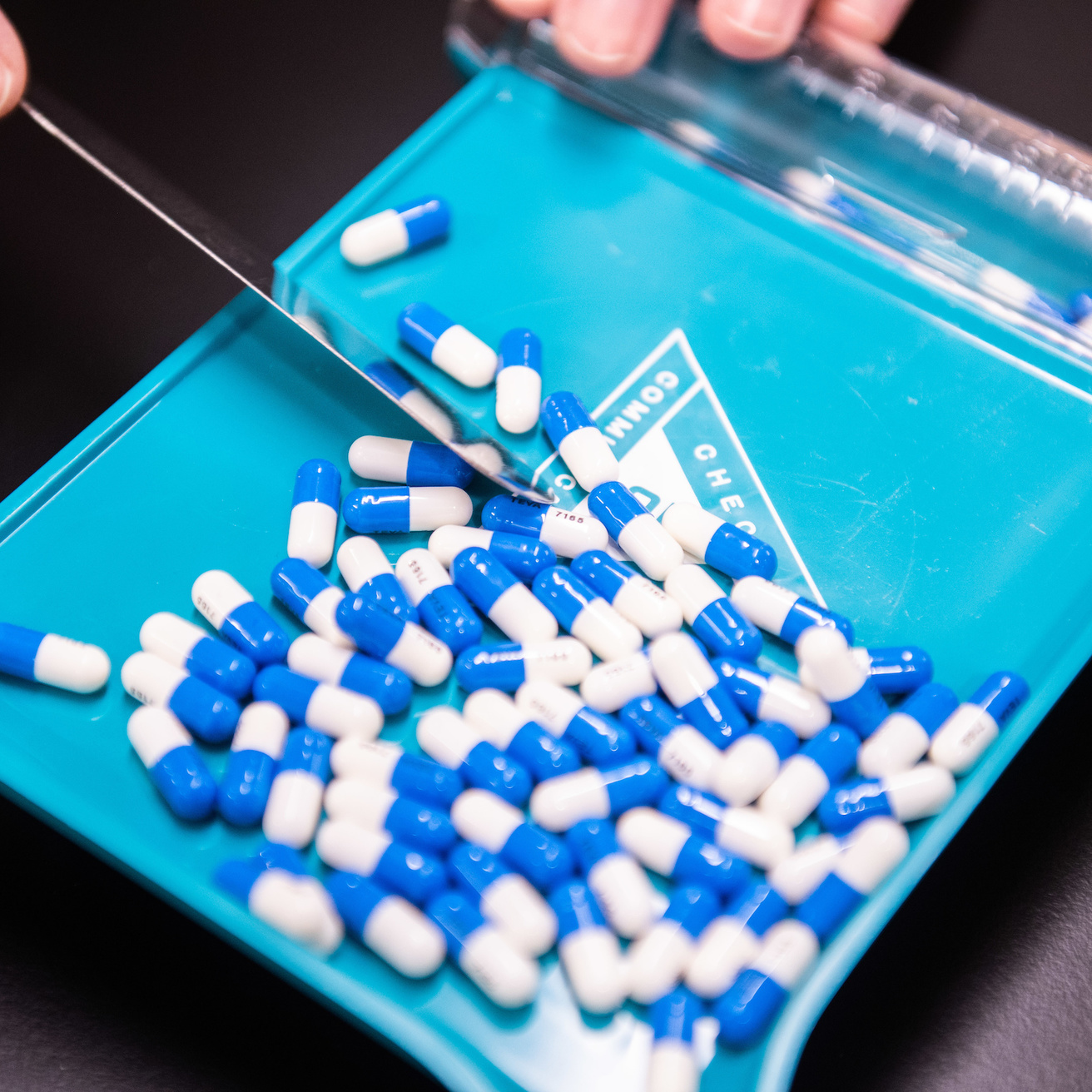 blue and white pill capsules on a light blue pill dispenser